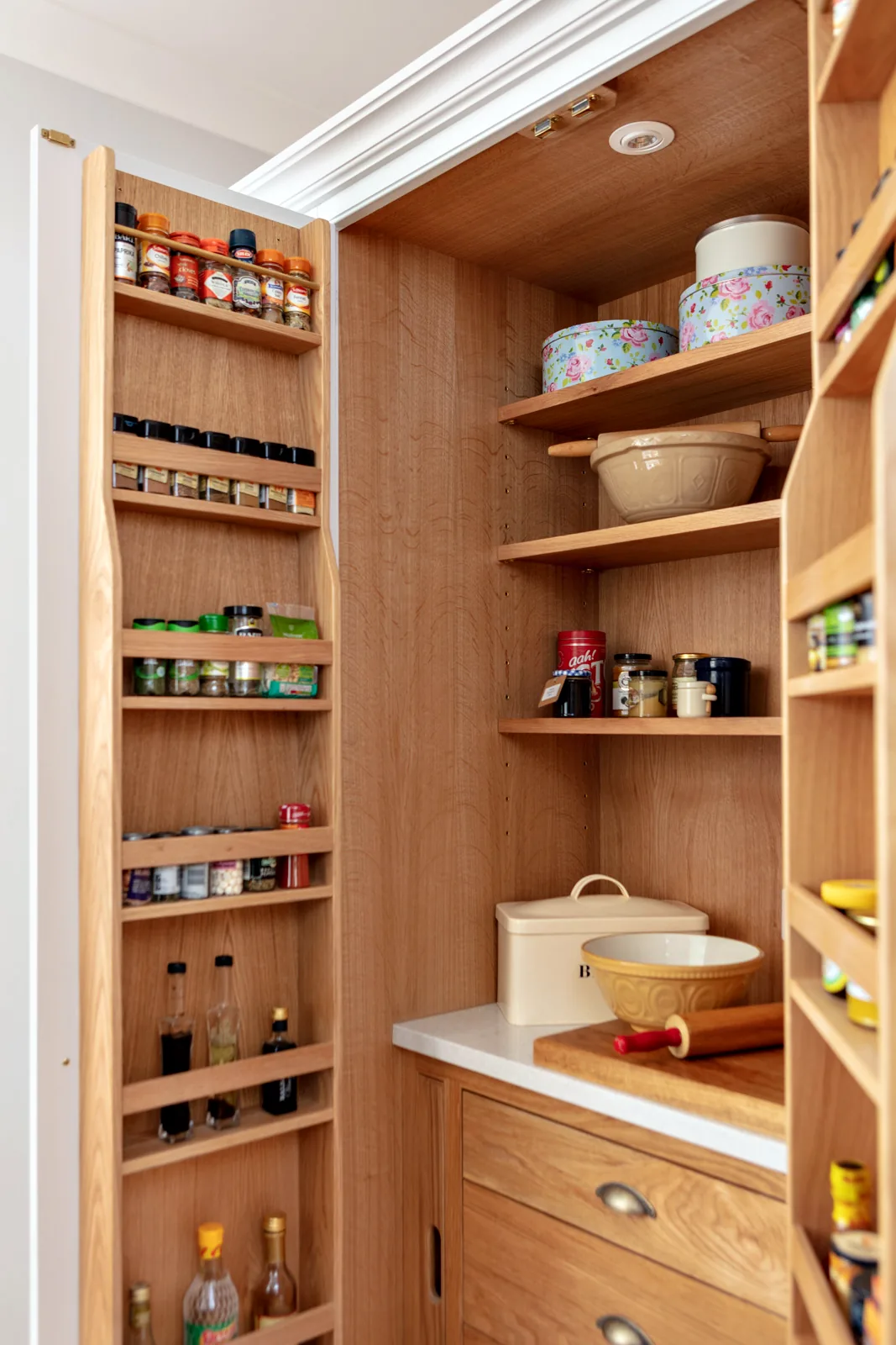 Oak lined larder with door spice racks, open shelves, a cold stone shelf and oak drawers