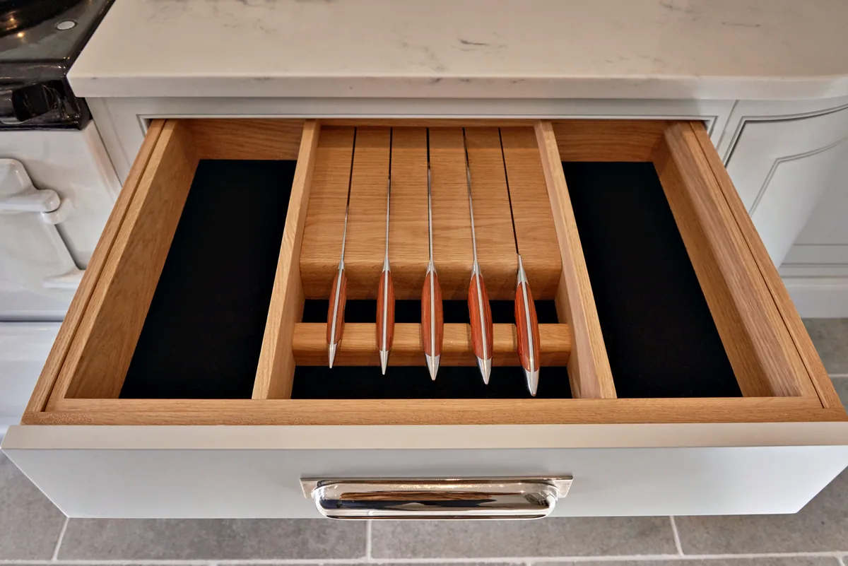 Oak knife drawer insert with utensil dividers below a marble effect worktop