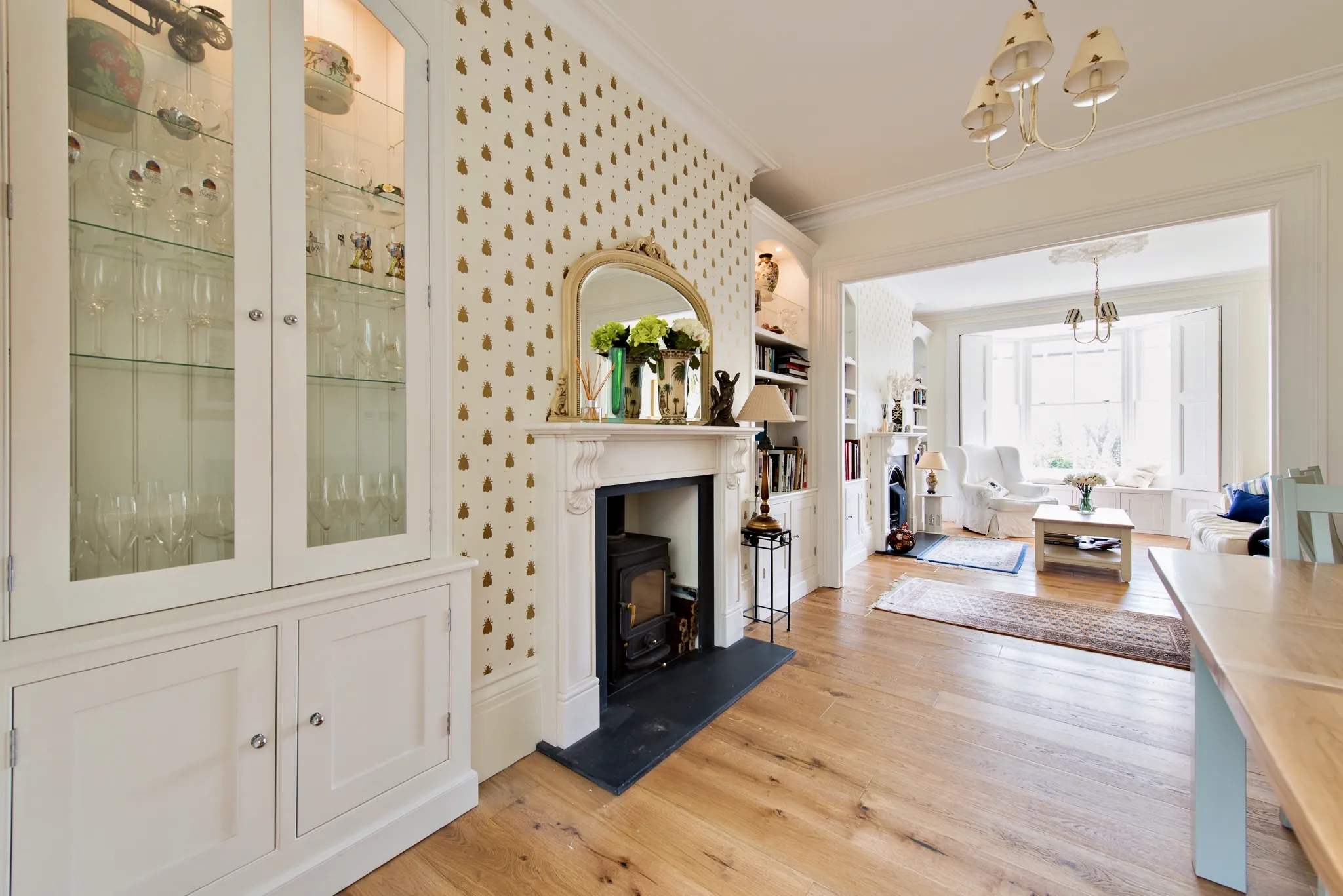 Dining room with pale glazed display cabinets beside a fireplace, opening through to the sitting room