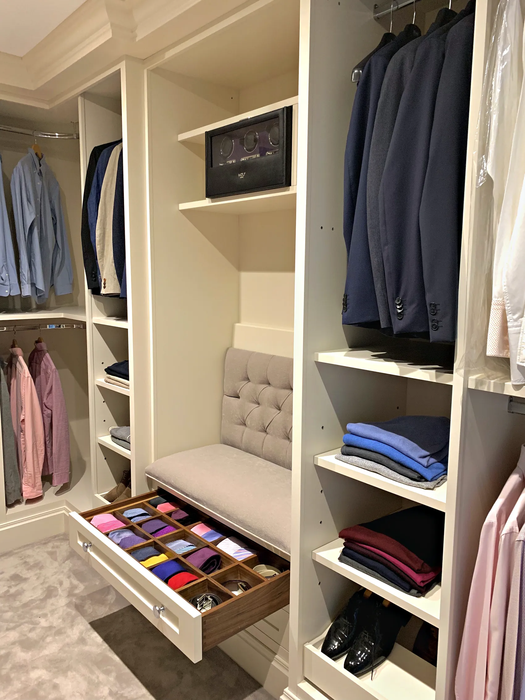 Dressing room with an upholstered bench, a pull out tie drawer and hanging rails for suits and shirts
