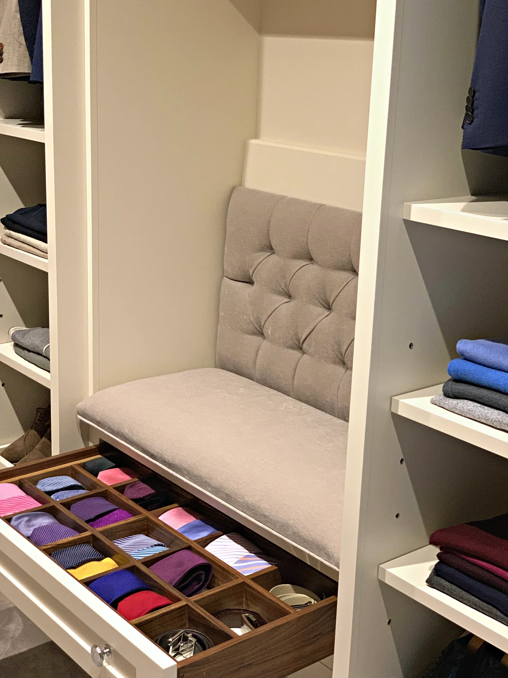 Dressing room with an upholstered seat above a pull out walnut tie drawer and open shelves