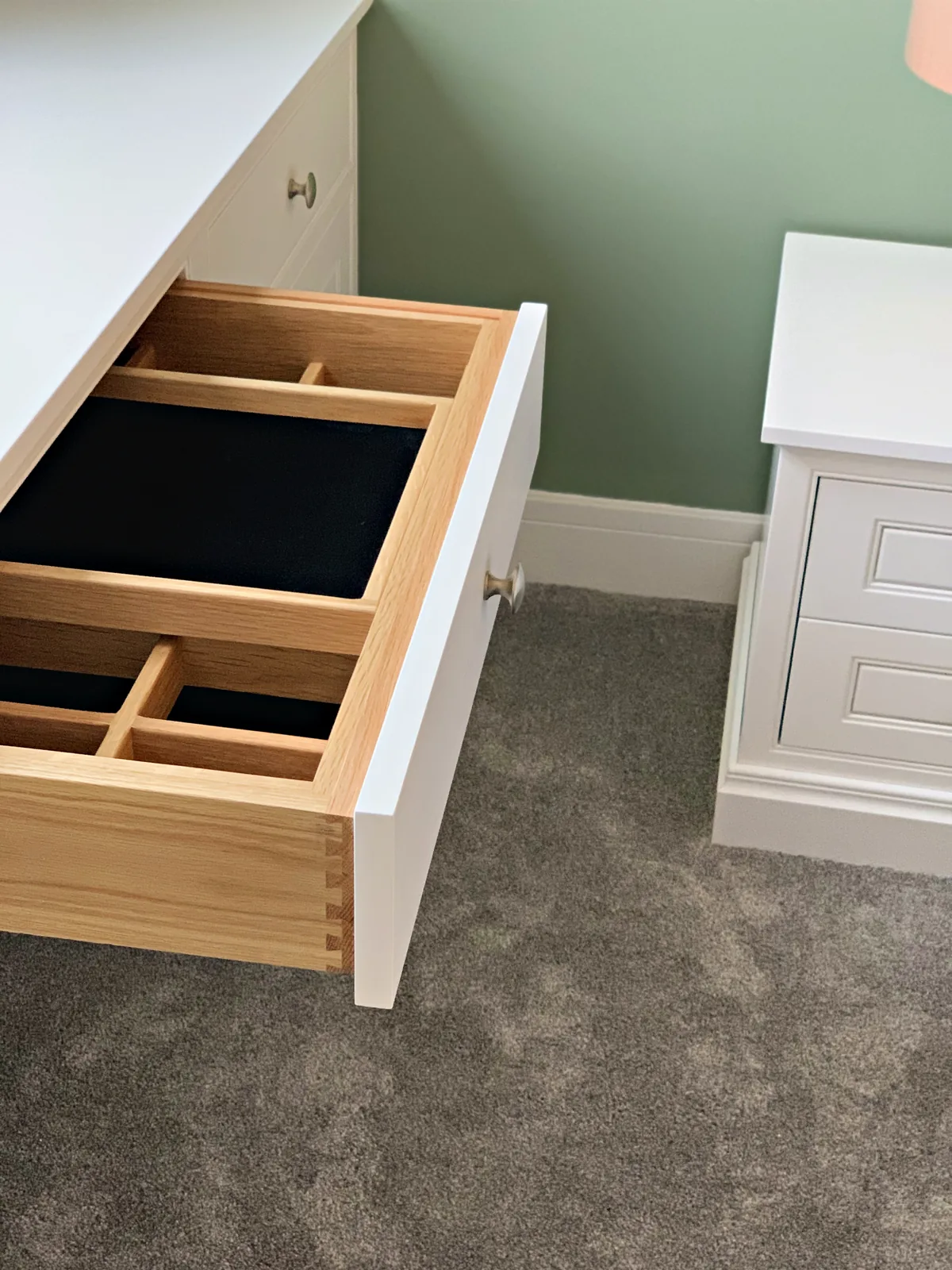 White drawer pulled out on a dovetailed oak box with lined dividers